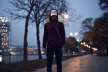 Athletic sporty man training in hoodie sweatshirt in urban city park.
