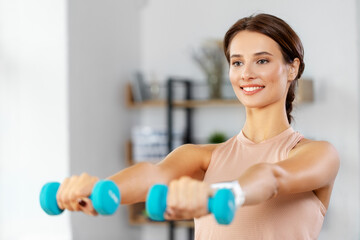 fitness, sport and healthy lifestyle concept - happy woman with dumbbells exercising at home