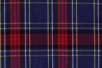 The texture of the woolen fabric in a check, reminiscent of tartan. Blue and red checkered fabric.
