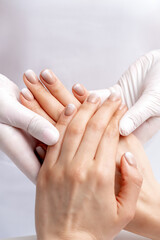 Manicurist wearing gloves doing wax massage on female hands with manicure in nail salon