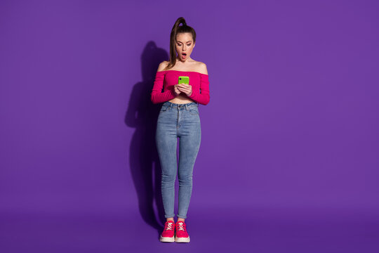 Full length photo of lovely surprised lady hands hold cell phone shocked wear pink uncovered shoulders top isolated violet color background