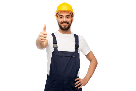 profession, construction and building - happy smiling male worker or builder in yellow helmet and overall showing thumbs up over white background