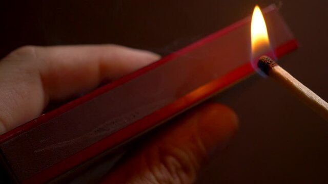 Macro footage of person inflaming a match on matchstick box.Slowmotion video.