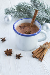 Hot cocoa with cinnamon in the metalic  mug  on the white wooden background