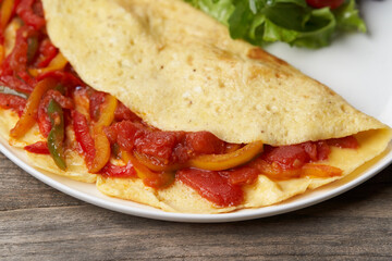 Omelette with vegetables on wooden background