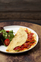 Omelette with vegetables on wooden background