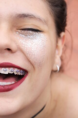 Teenage girl smiling, with make-up and glitter on her face
