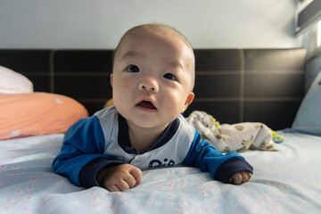 Adorable baby boy during tummy time on bed. Newborn child relaxing in bed