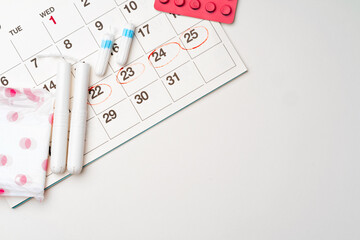 Fototapeta na wymiar Menstruation calendar with sanitary pads and tampons, pills