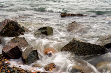 Waves at the seashore or pier captured with a slow shutter speed. Natural abstract motion background.
