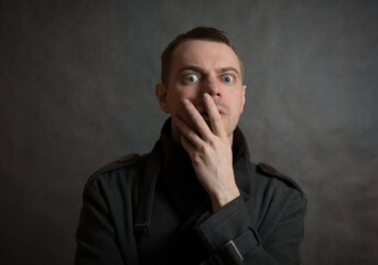 Man in coat on dark background with surprised face.