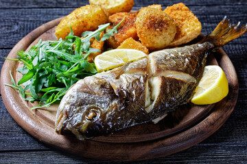 Whole roasted dorado fish with potato, top view