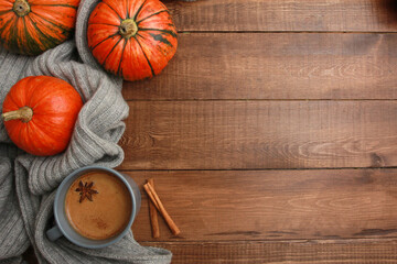 Grey cup of coffee with milk and spices, knitted scarf, orange pumpkins on dark brown wooden table. Autumn drink concept. Fall, pumpkin spicy latte, thanksgiving, top, copy space