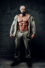 Fototapeta na wymiar Handsome and powerful athlete with naked torso and perfect abs and with beard and moustache poses in dark background.