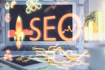 Double exposure of table with computer and seo drawing hologram. Search optimization concept.