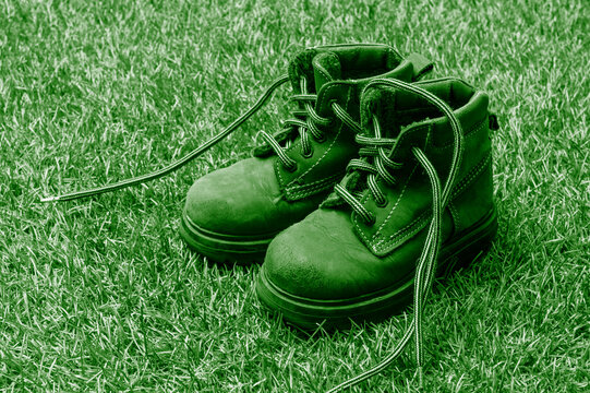 Kids fashion green boots on green grass background. The concept of the coming winter, selling shoes for children.