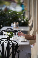 Woman reading book and drinking coffee at cafe, outdoors