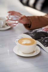 Woman reading book and drinking coffee at cafe, outdoors