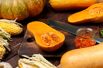 Small pumpkin cut into halves on wooden cutting board with knife