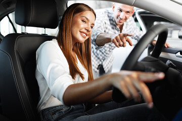 Young attractive woman looking for a new car in a showroom