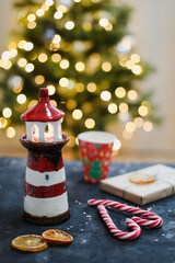 Christmas decorations, candles, candy cane, orange slices against Christmas tree with bokeh lights