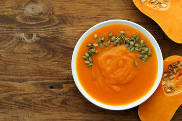 Top view of pureed pumpkin soup in a white bowl on dark table