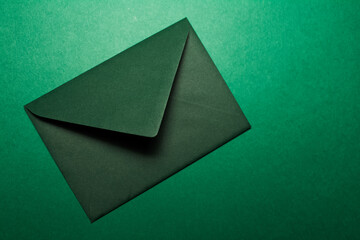 Close-up of paper envelope of green color isolated on background of textured green wall.
