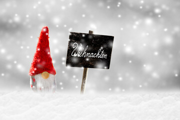 Kleiner Weihnachtsmann im Schnee mit Schild "Weihnachten"