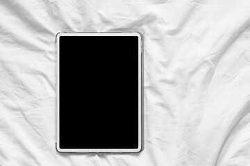 Top view mockup image of white tablet pc with blank desktop white screen on a cozy white bed at home