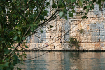 Fototapeta na wymiar Cliff above a lake with people jumping in