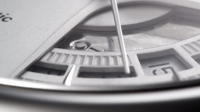 Second arrow passing by on metallic clock face with beautiful guilloche detail and set date 