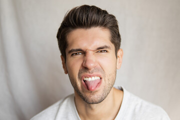 Portrait of a young attractive man showing a denied face expression with his tong out