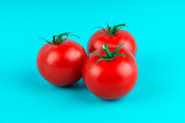 three red, ripe tomatoes on a blue background
