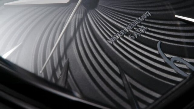 Closeup of black swiss water resistant watch with running second arrow and ribbed clock face 