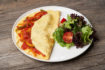 Omelette with vegetables on wooden background