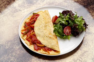 Omelette with vegetables on wooden background