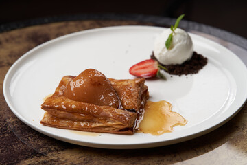Puff pastry cake with caramel syrup, baked pear and ice cream