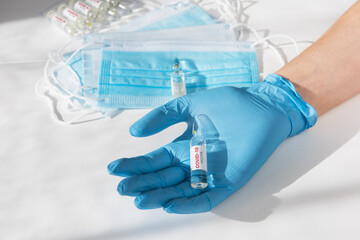 Coronavirus vaccine concept: covid-19 vaccine in hand with blue protective gloves.