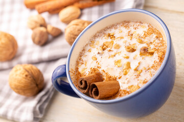 Blue cup of salep milky hot drink of Turkey with cinnamon powder and sticks healthy spice and autumn winter içeceği on white rustic vintage wooden table.