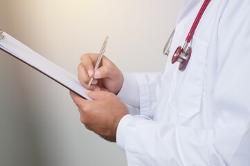 Close up Physician in white coat, stethoscope writing paper on clipboard by.pen isolated on white background.