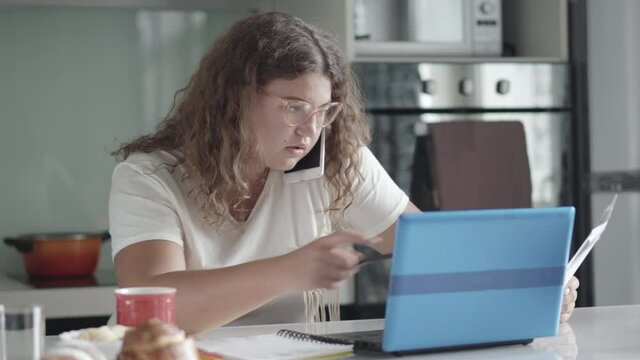 Busy Obese Businesswoman Talking On The Phone And Typing On Laptop Keyboard At Home. Portrait Of Concentrated Caucasian Woman Working Online During Lockdown. Freelance And Remote Working.