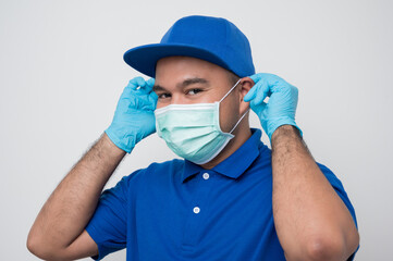 Fototapeta na wymiar Blue delivery asian man wearing protection mask and medical rubber gloves on isolated white background safety deliver concept.