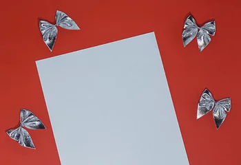 Fotobehang Wit vel papier op rode achtergrond met strikken van zilverfolie © Albert Ziganshin