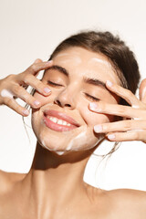 Beauty and skin care concept. Topless woman smiling while cleaning her face with nourishing...