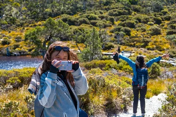 Fotobehang Cradle Mountain Smiling young Asian Chinese female lady doing mobile phone travel shoot