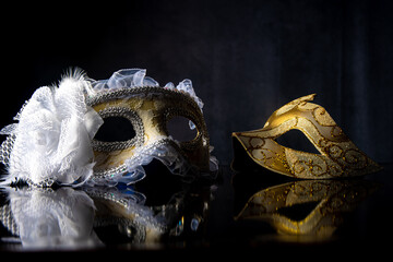 Carnival venetian masks on black surface, low key image, directed light, selective focus.