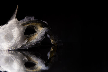 Carnival venetian masks on black surface, low key image, directed light, selective focus.
