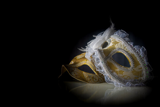 Carnival venetian masks on black surface, low key image, directed light, selective focus.