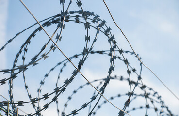 Barbed wire fence on the european and world border against blue skies on a sunny day