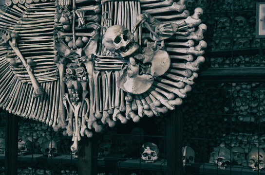 Kutna Hora, Czech Republic, May 14, 2019: Royal coat of arms made of human bones and skulls with pile of skulls background. Kostnice Church in Kutna Hora.